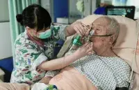 Медсястра выцірае рот шпіталізаванаму сталаму мужчыне
