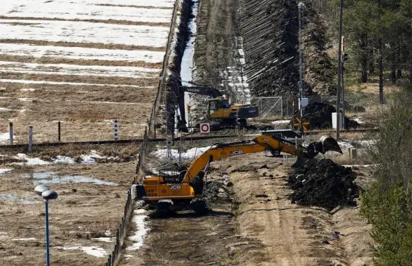 Экскаваторы копают песок возле пограничного забора с Россией / Reuters
