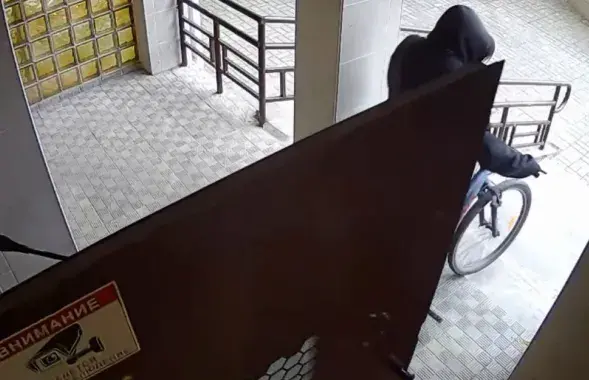 Украденный велосипед выносится из подъезда дома / Скриншот видео минской милиции
