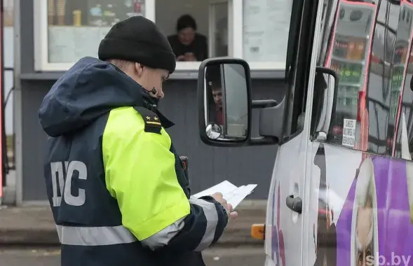 Сотрудник ДПС проверяет документы у водителя маршрутного такси
