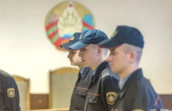 Міліцыянеры на фоне дзяржаўнага герба Беларусі
